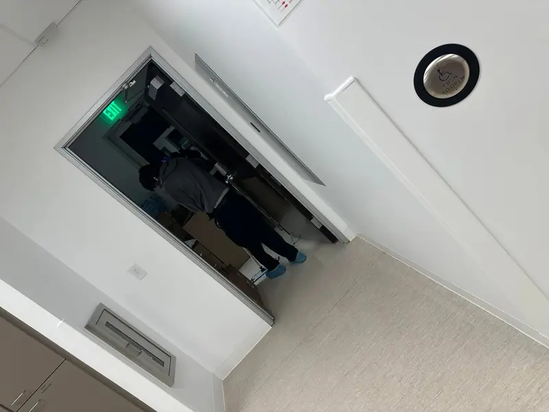 Clean commercial hallway with accessible door push plate and open office doorway, suitable for office cleaning services