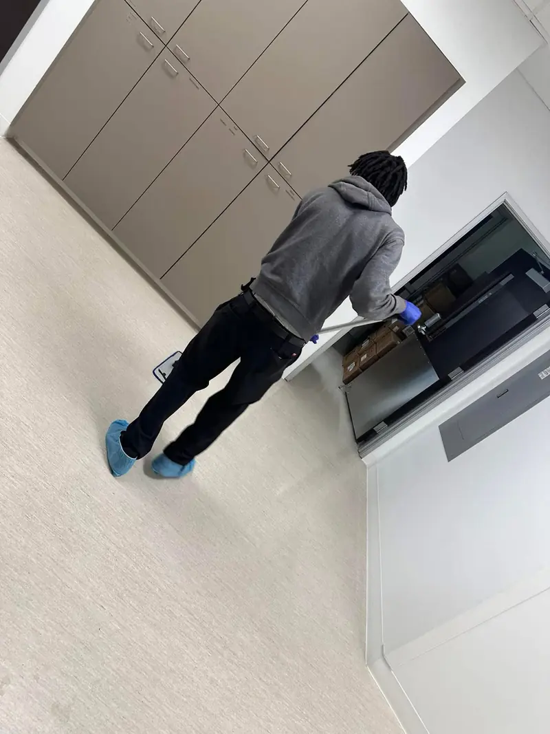 Janitor mopping a light commercial office floor wearing shoe covers and gloves for professional office cleaning